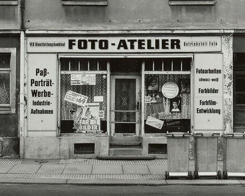 2025_09_presse_ymy_timeandagain_02 - Schwarzweißfotografie des Fotoateliers des VEB Dienstleistungskombinats in Dresden im Jahr 1990.